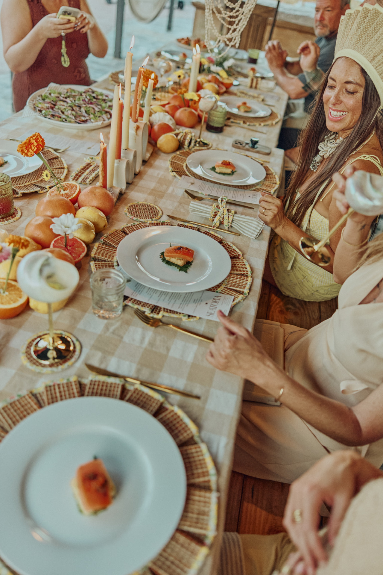 Guests laughing around a long candlelit table set for a private dinner
