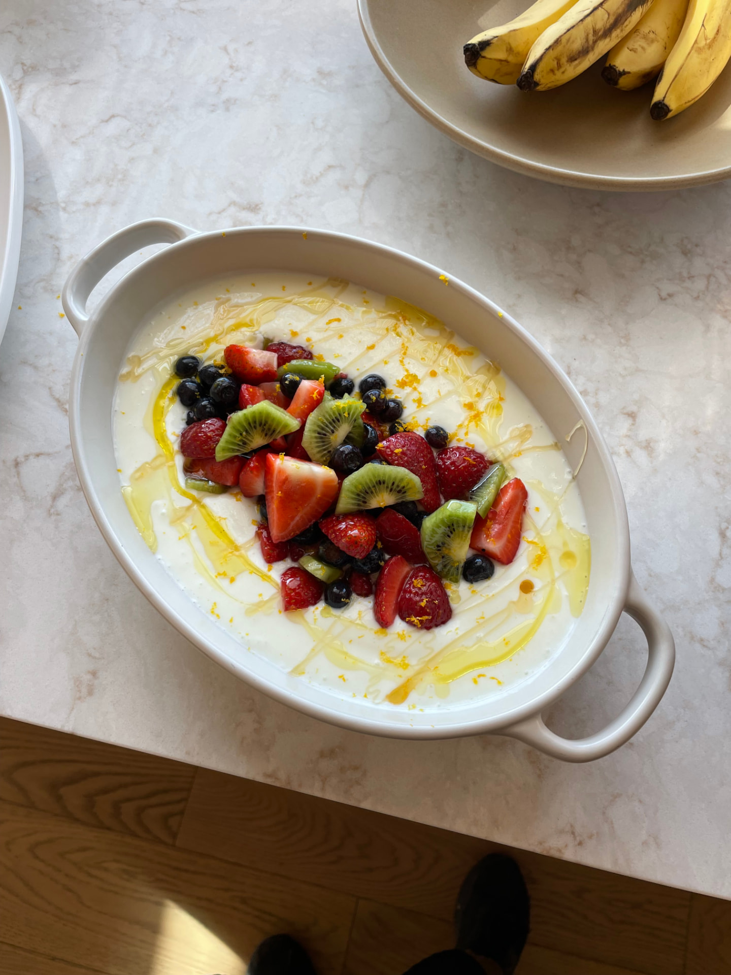 Dish of yogurt with fresh strawberries, kiwi, blueberries, honey and citrus zest
