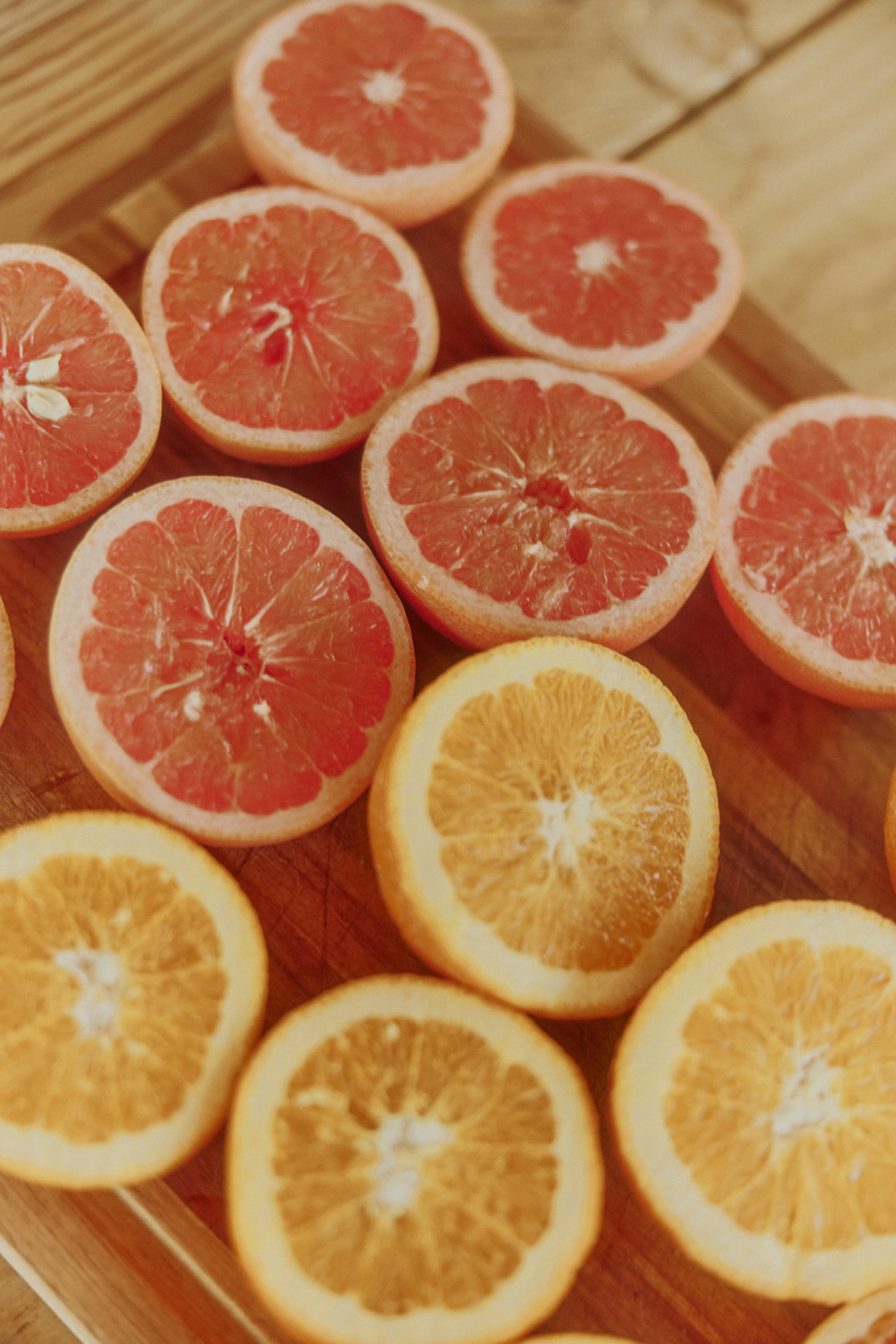 Halved grapefruit and oranges on a wooden board