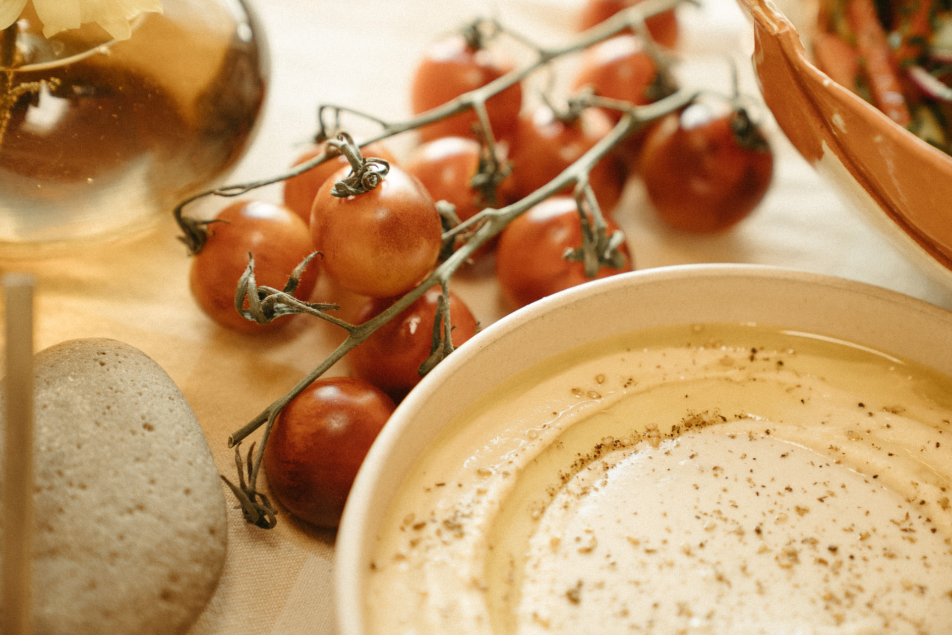 Bowl of hummus with olive oil beside vine tomatoes