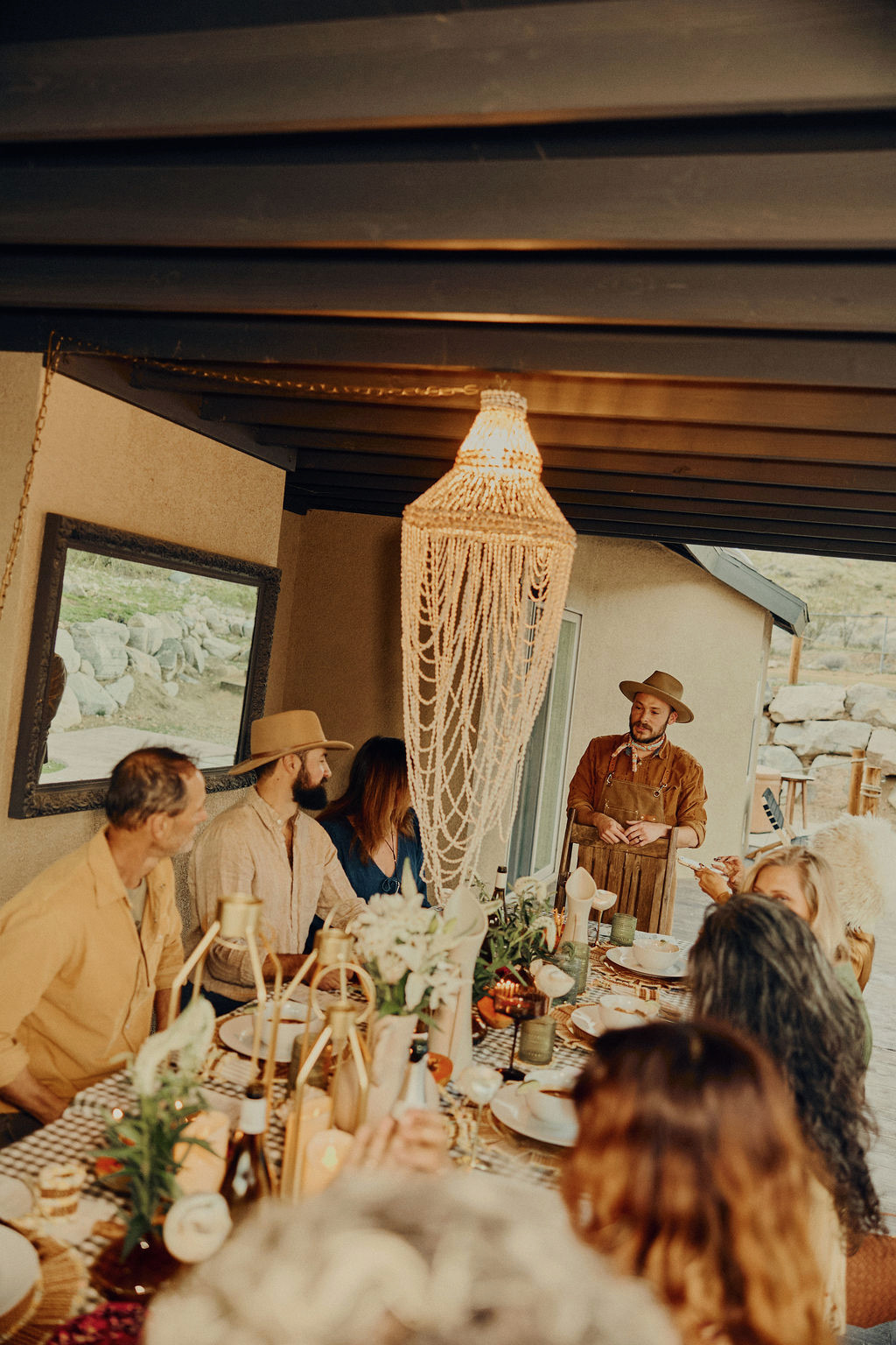 Chef Daniel in his apron serving guests beneath a beaded chandelier
