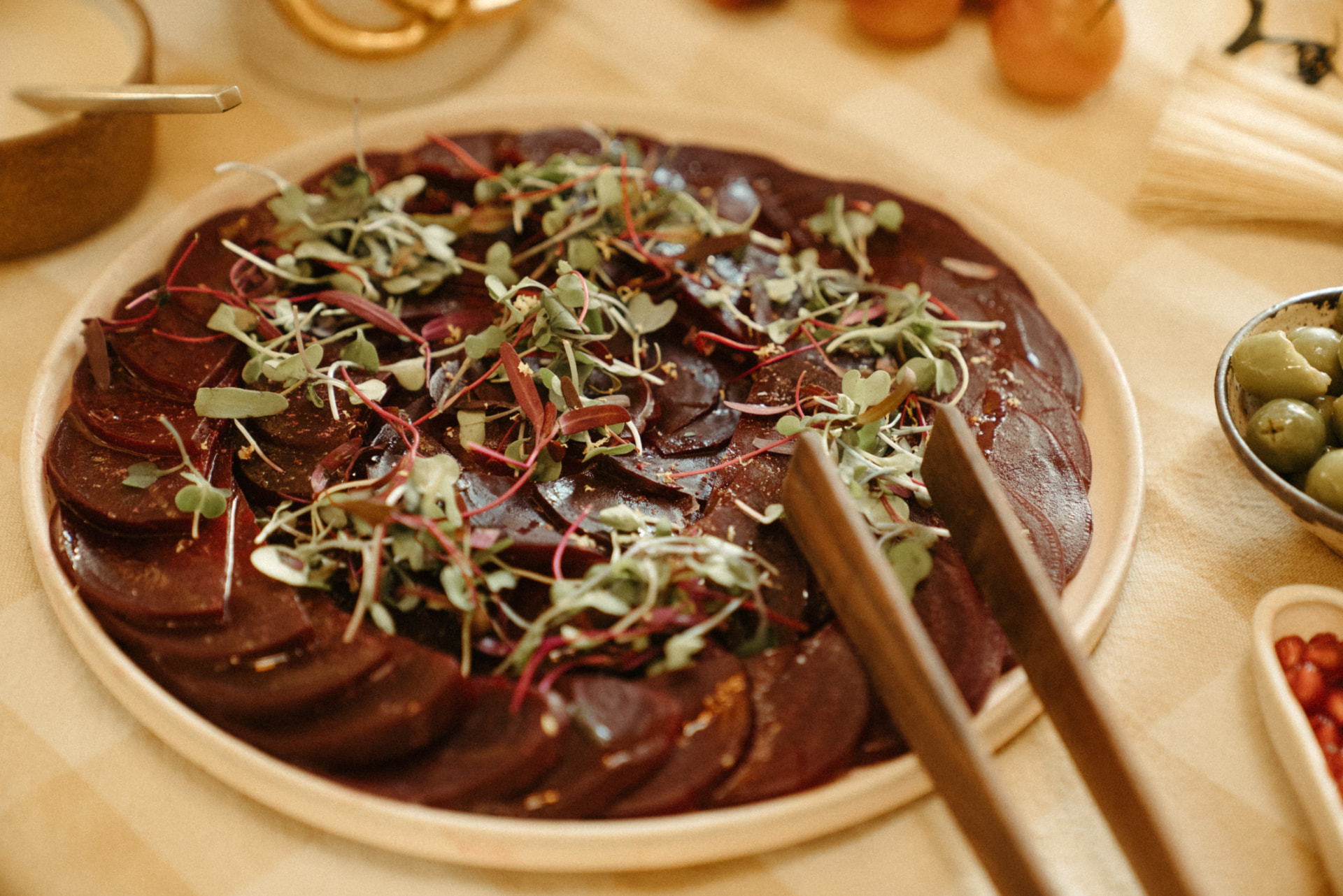 Beet carpaccio fanned on a ceramic platter with micro greens